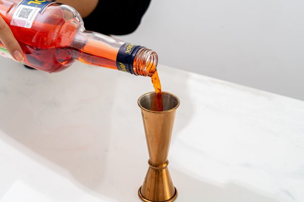 a bottle of Aperol being poured into a jigger