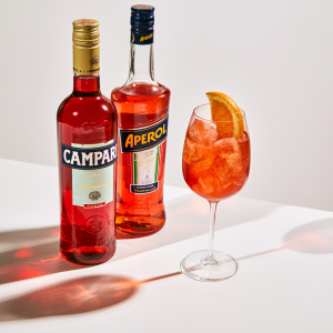 bottles of Campari and Aperol with a glass of Campari and champagne with an orange wedge