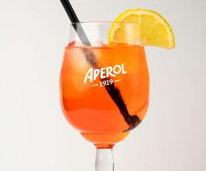 a wine glass printed with the word "Aperol" with a cocktail, orange slice, and a straw