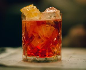 a rocks glass with ice, holding a red cocktail