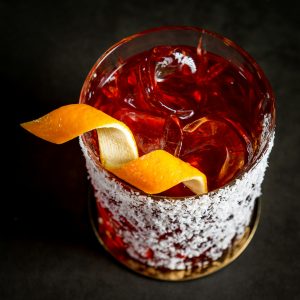 top-down photo of a very red cocktail with an orange twist, made with Campari liqueur