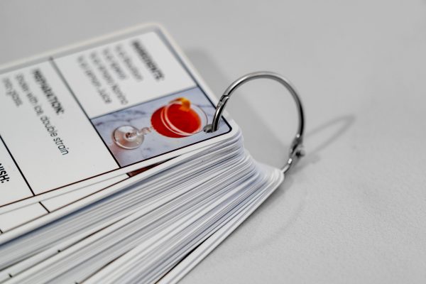 Close-up of 50 cocktail recipes in one deck, connected by a metal ring